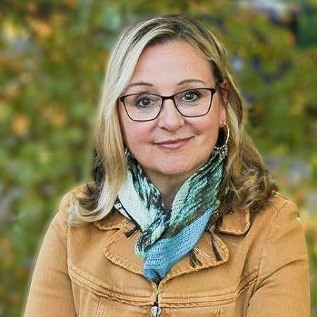 Kim Hornsby, a young white woman with blonde hair and glasses wearing a stylish yellow jacket with a blue scarf